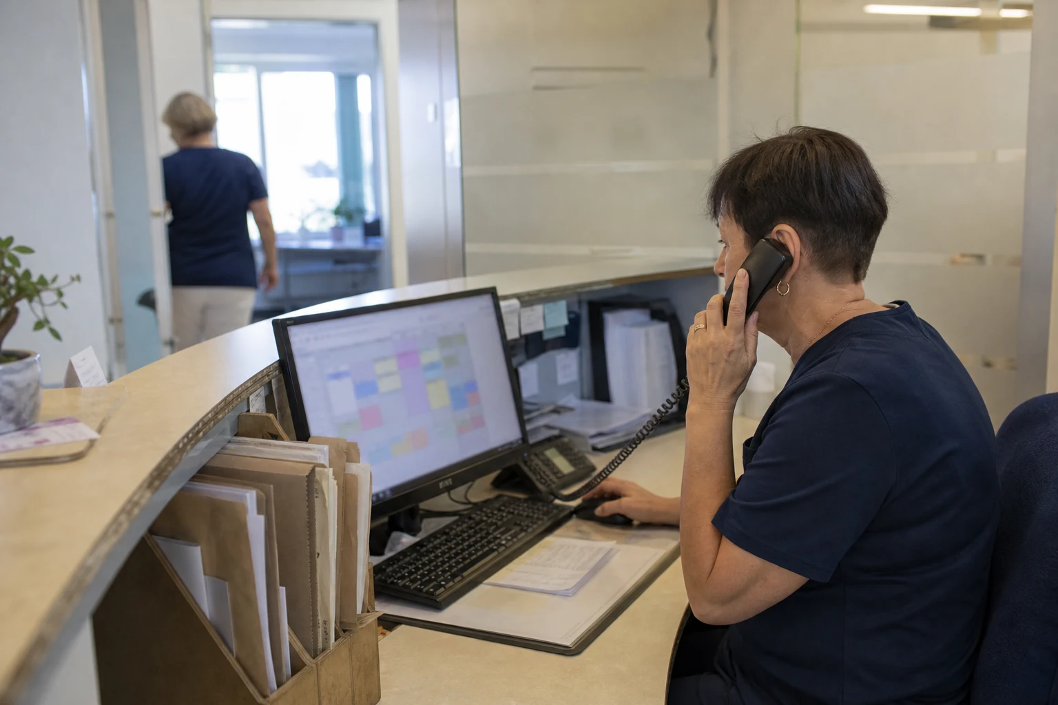 Medizinische Fachangestellte nimmt in einer Arztpraxis einen Telefonanruf am Empfang an
